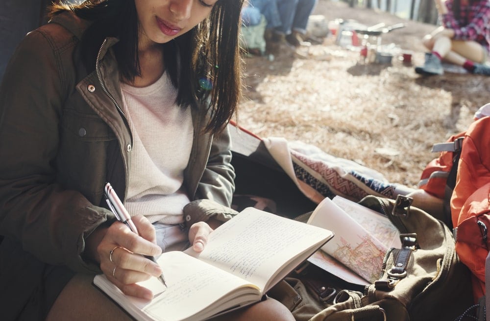 A woman writing in her journal while camping