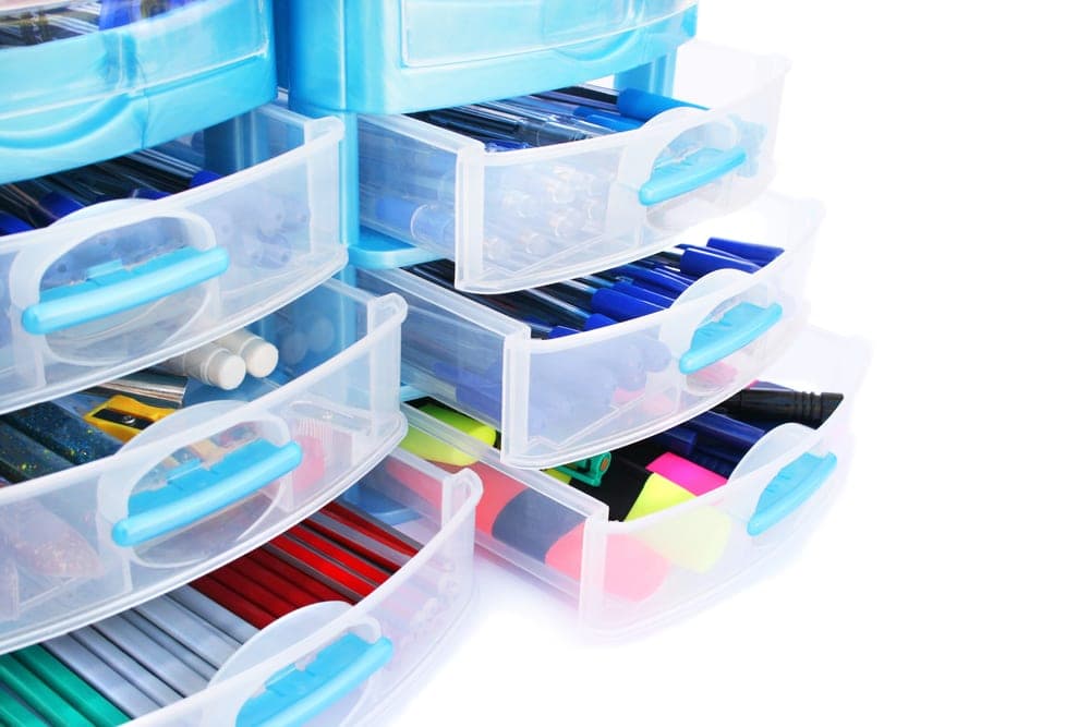 Blue plastic drawers with office supplies in it