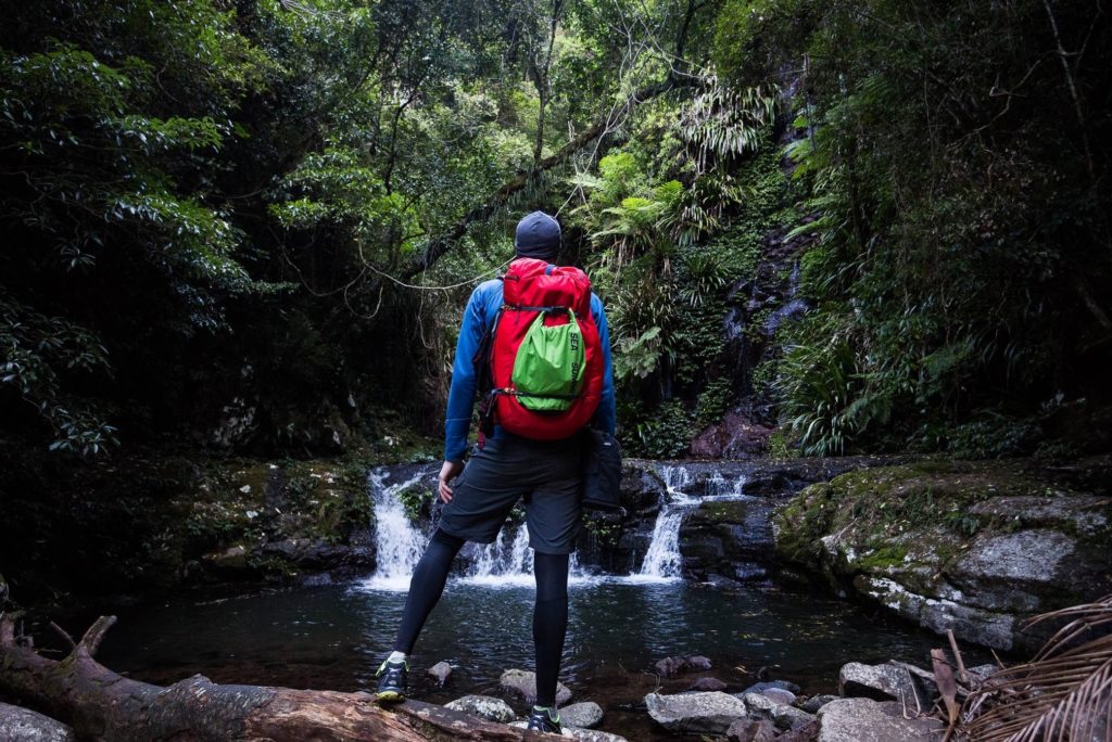 A hiker looking at a river carrying a duffle bag