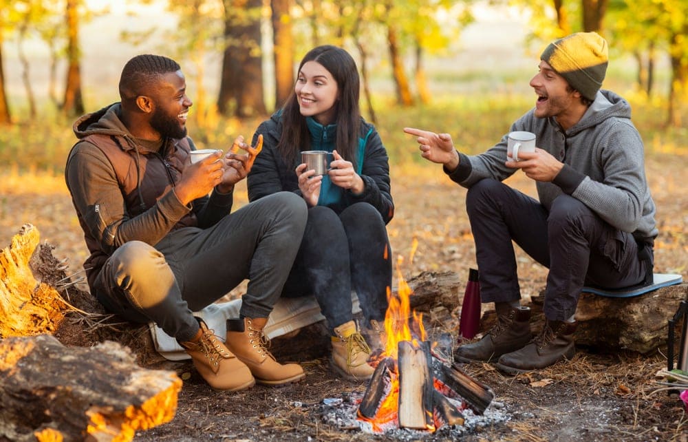 Friends wore jacket and coat while sitting beside campfire