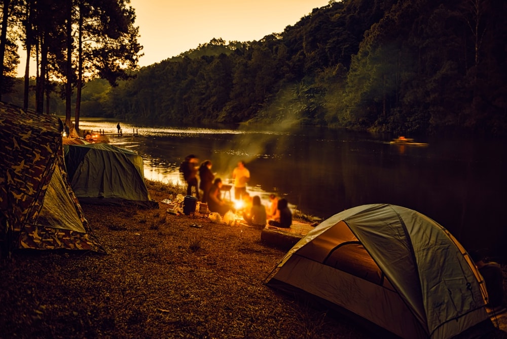 Group of people camping beside the river in twilight hour