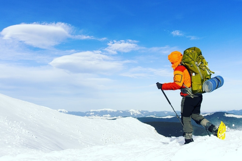 Winter hiking on snowshoes with a layered clothes and backpack