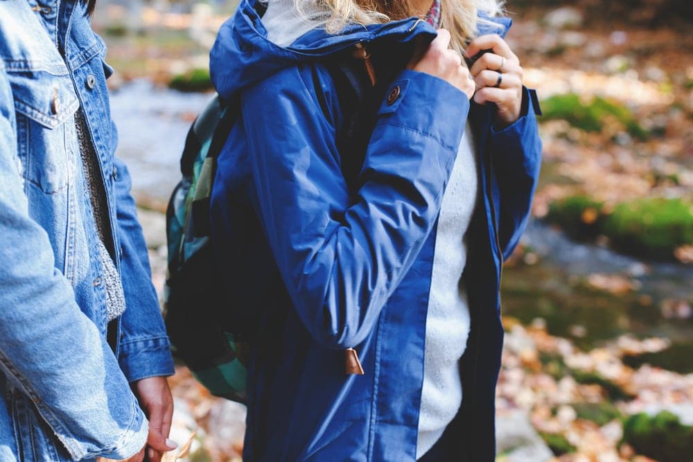 Blue jacket and parka wore by two hikers near river