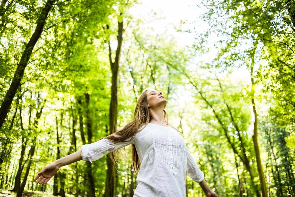 Woman enjoying sunlight in the forest