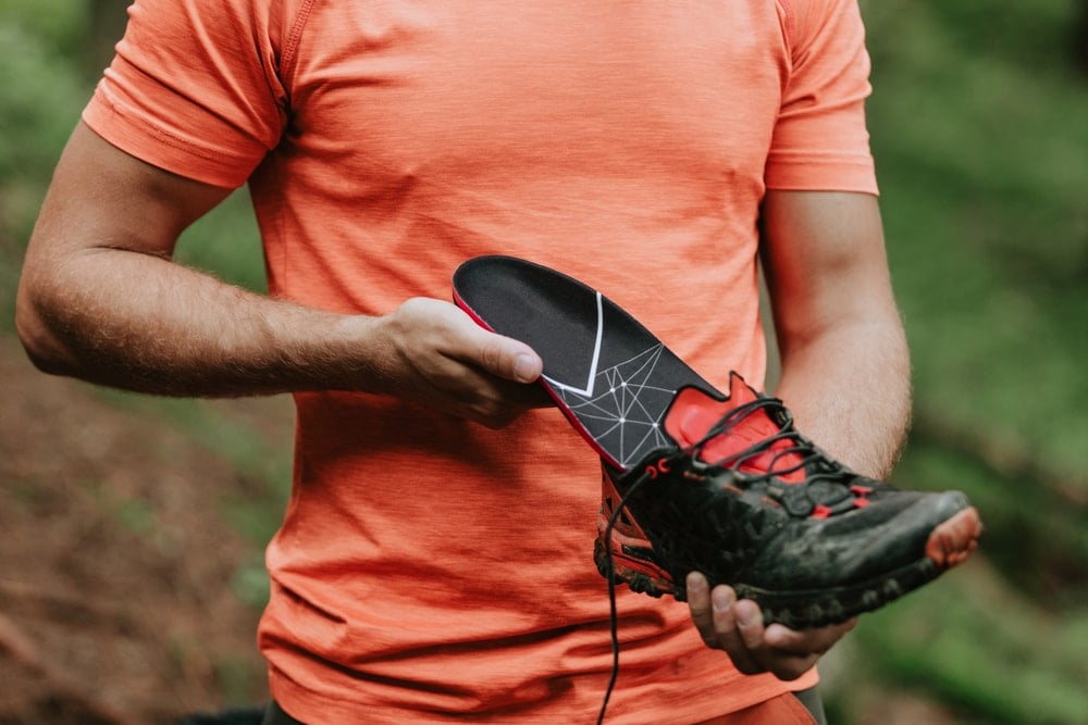 A man holding a shoes and a heated insoles