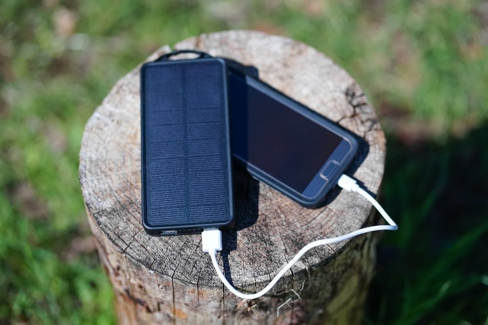 Phone connected to a solar powerbank on the woods