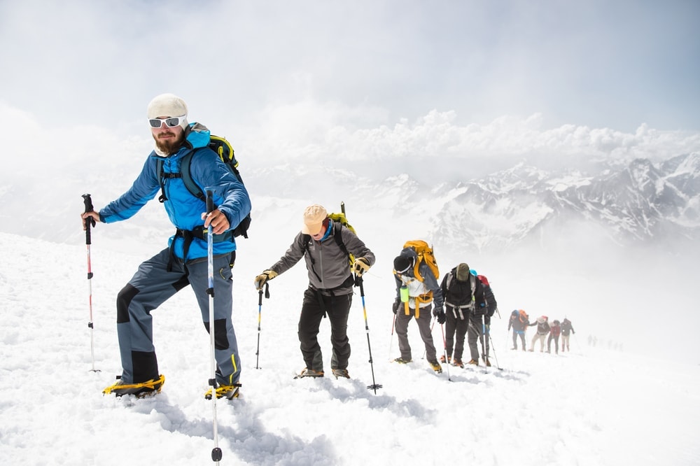 Outdoor guide leading a group of hikers on a snowy mountain