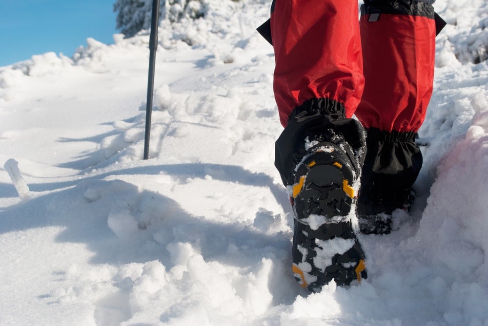 Shoe sole of a hiking boots wore by a hiker wearing a gaiter and using trekking pole