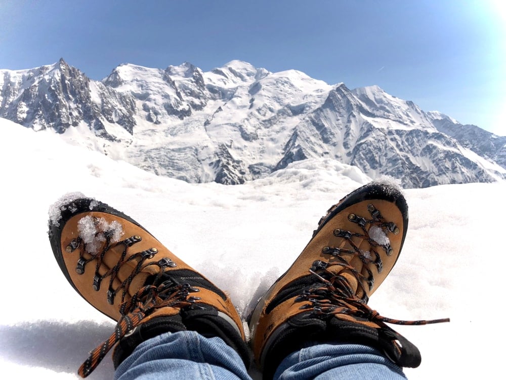 Hiking shoes touching the snow with mountain view