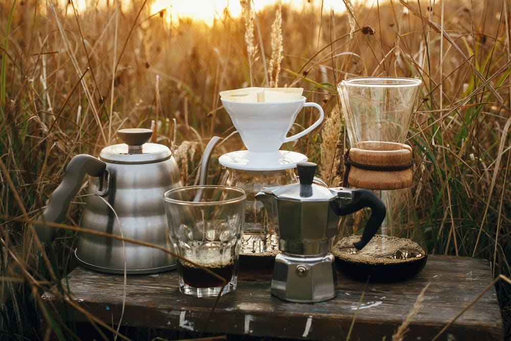 Camping coffee makers on a sunny background in rural herbs