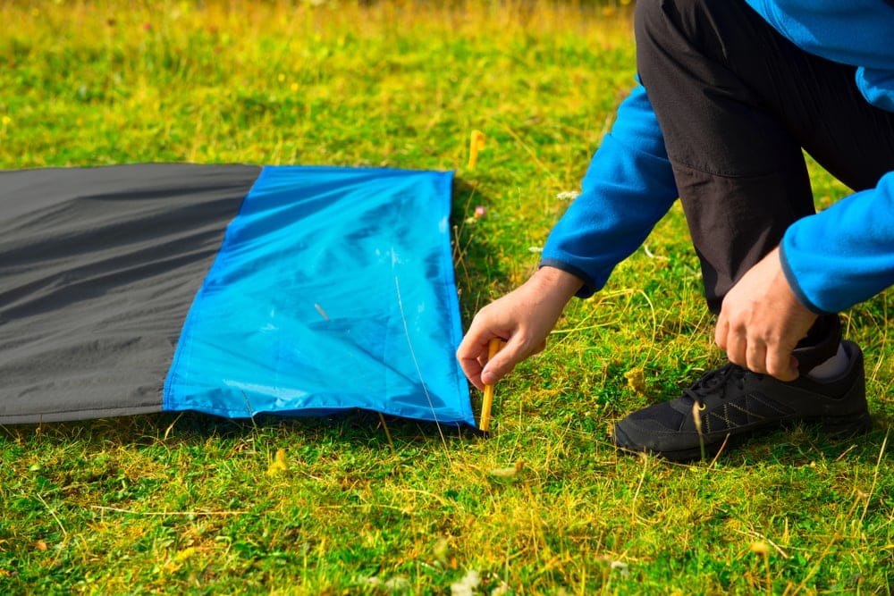 Man setting up a camping footprint for additional safety when cowboy camping