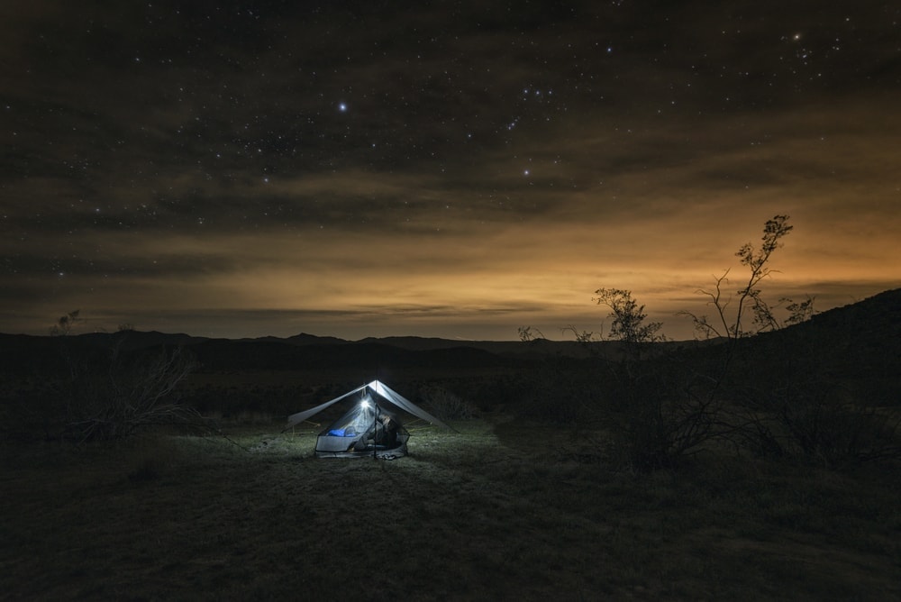 Tarp shelter set up on a flat ground under starry night sky