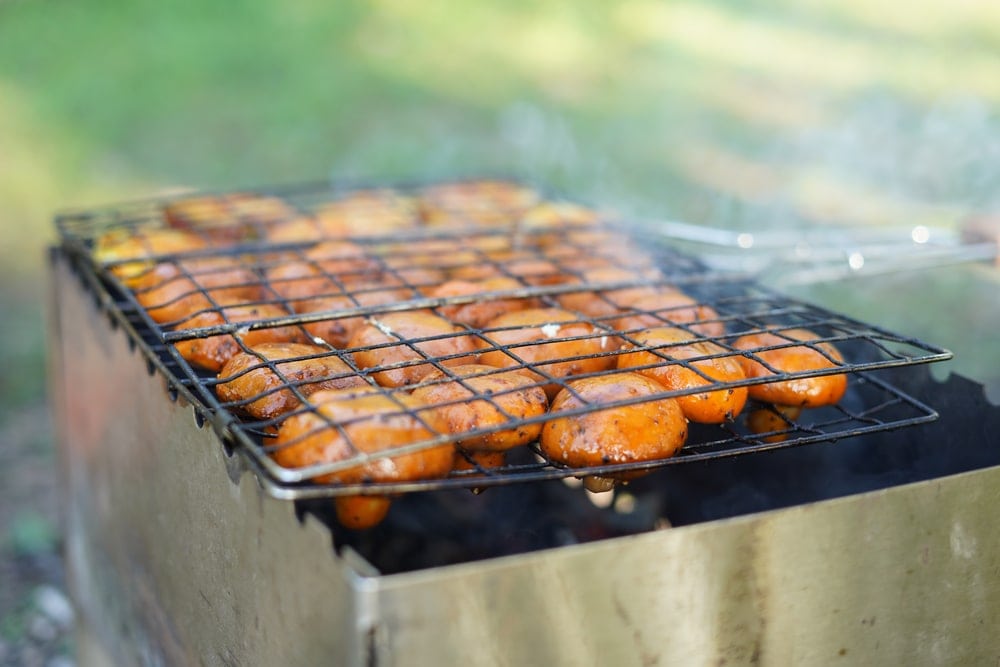 Mushrooms being cooked in a camping basket grill