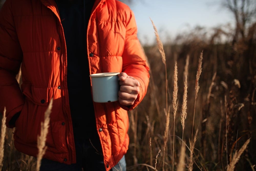 Man wearing a jacket holding a cup of coffee 
