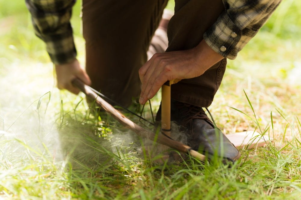 Man starting a fire using the bow drill method