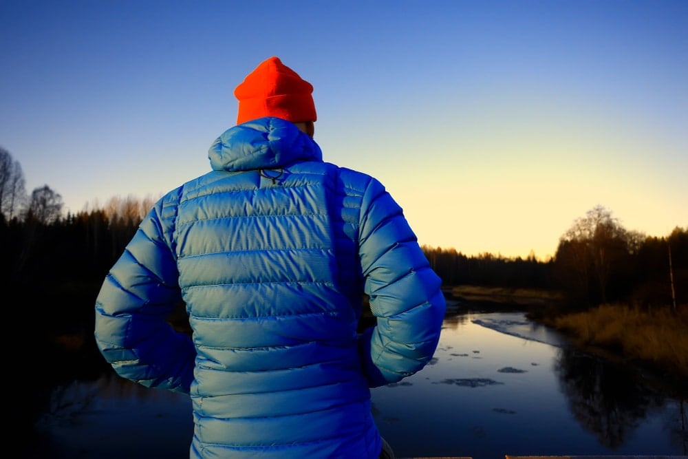 Man in a winter jacket looking over sunrise