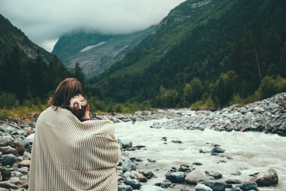 Couple wrapped in a cotton blanket looking at the river
