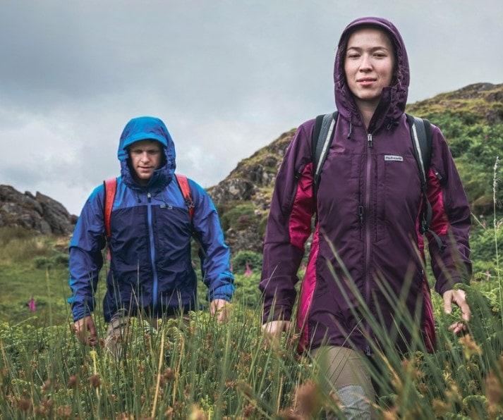 Man and woman walking through grass wearing Paramo jacket
