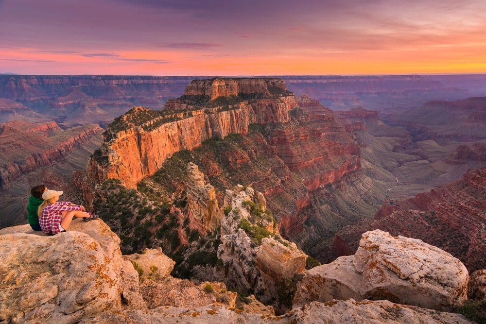 hikers watching the sunset view of the the Grand Canyon National Park