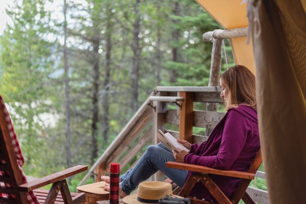 Girl sitting in a tree house reading a book