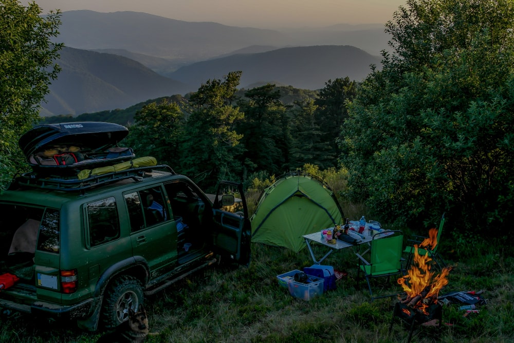 a car, tent, and camping supplies on a campground