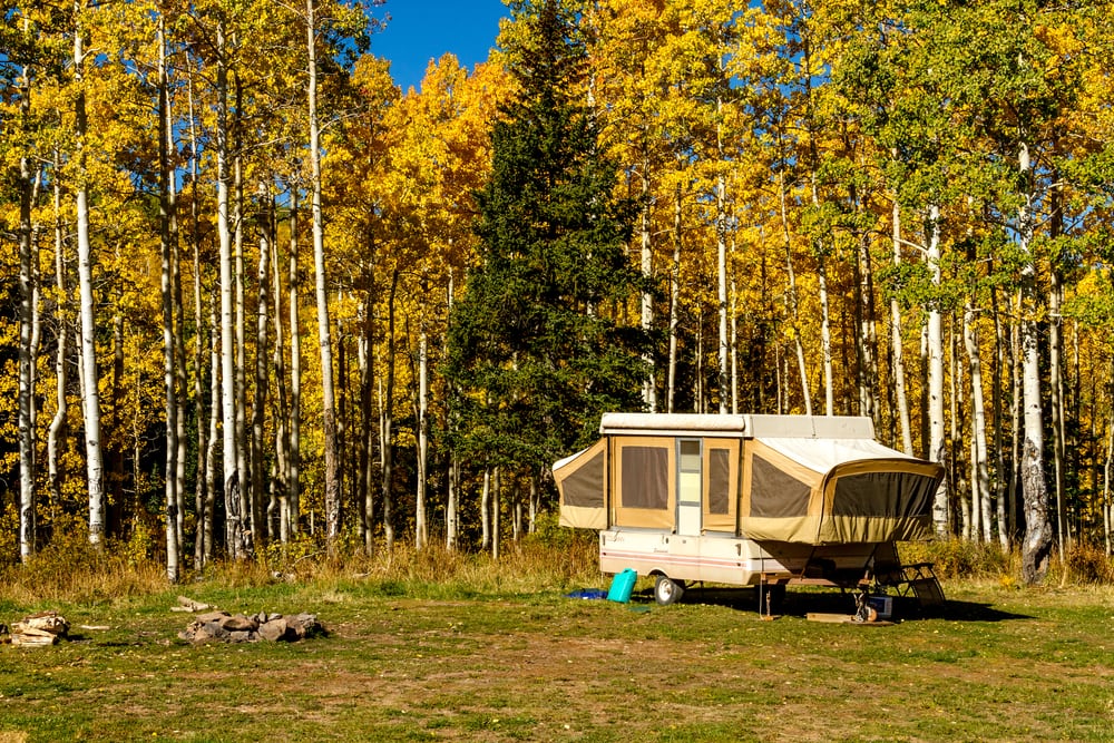 a pop-up camper in the middle of the forest.  Tent trailer camping is one of the  camping styles and is almost similar to RV camping
