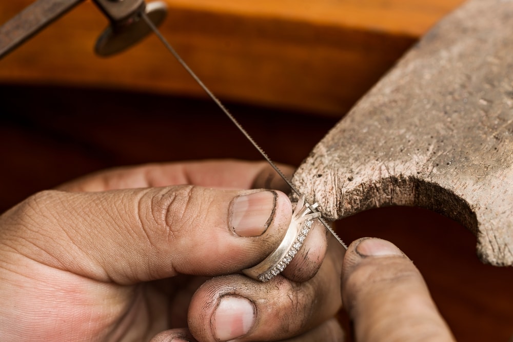artisan making a ring with gems using a small saw in a workshop
