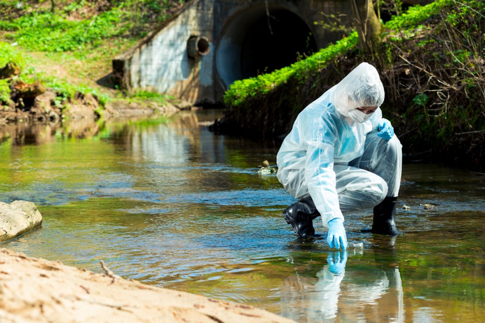 a man in protective suit collecting water samples to check for contamination