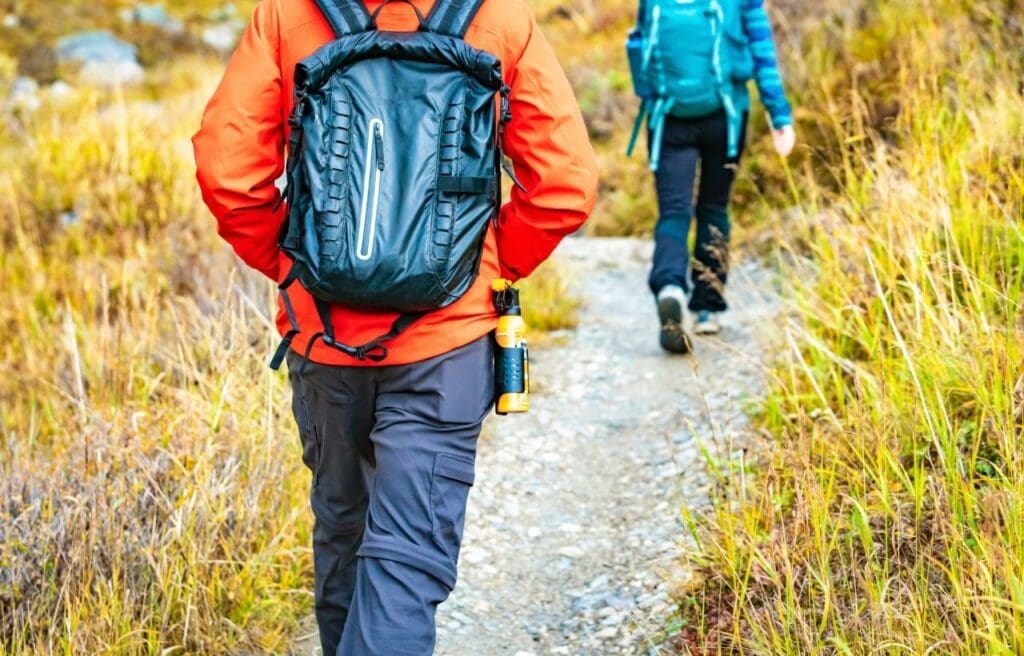 a hiker with a bear spray attached on its backpack
