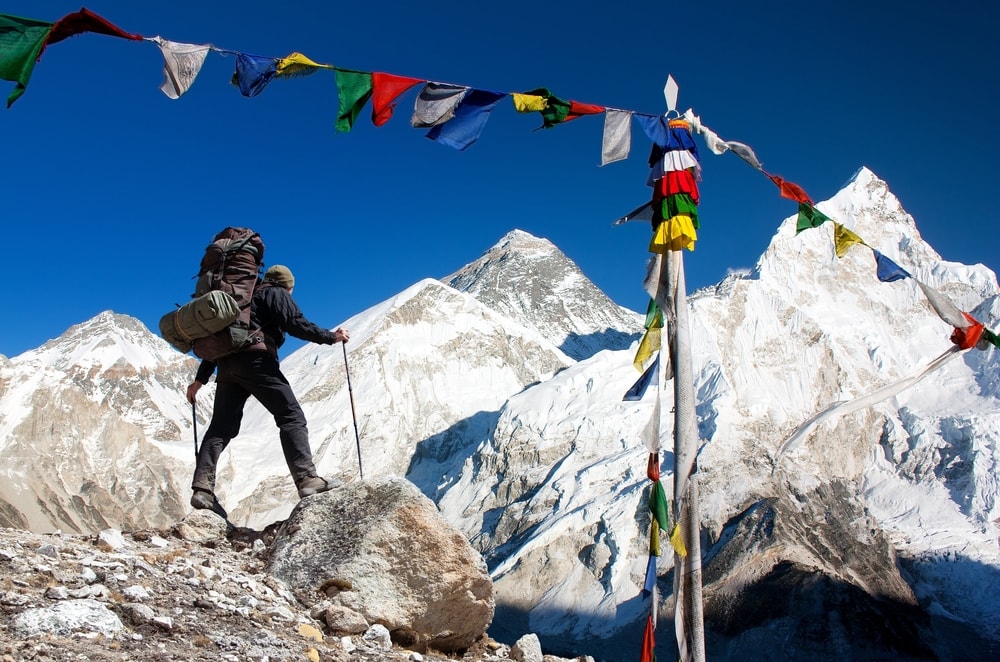 View of Mt. Everest with a climber and Buddhist prayer flags 
