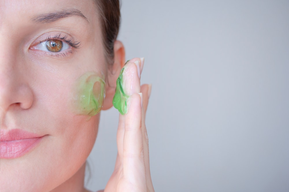 image of a woman putting a green cream on ger face
