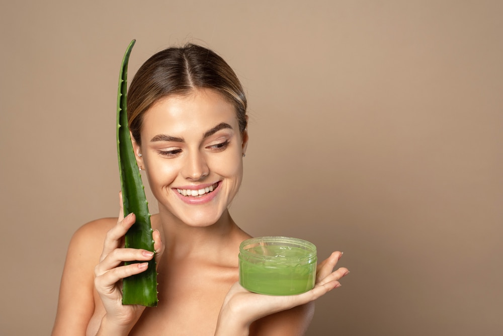 a woman holding an aloe vera plant and aloe vera gel in a container