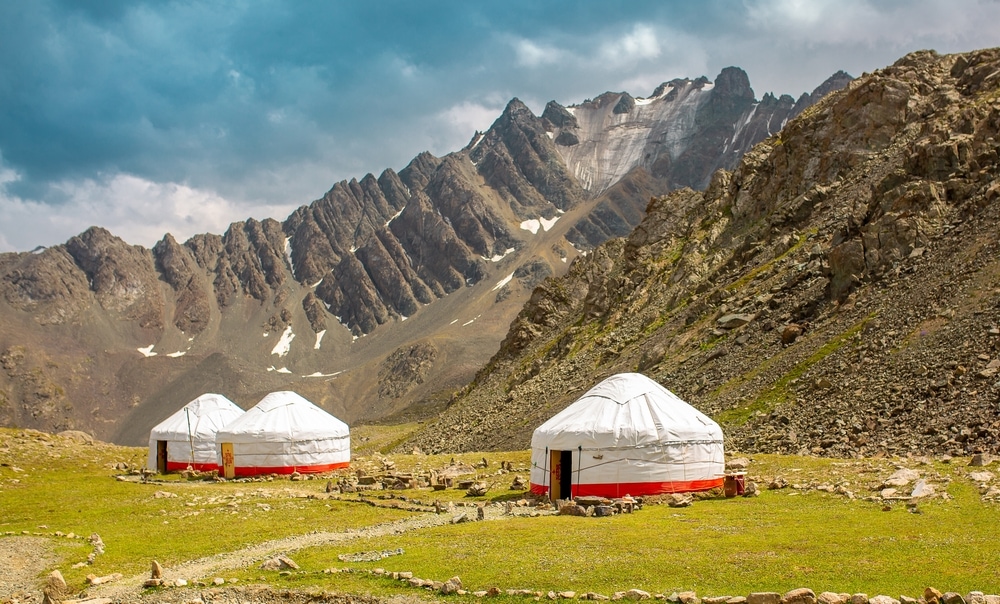 Three yurts below rocky mountains