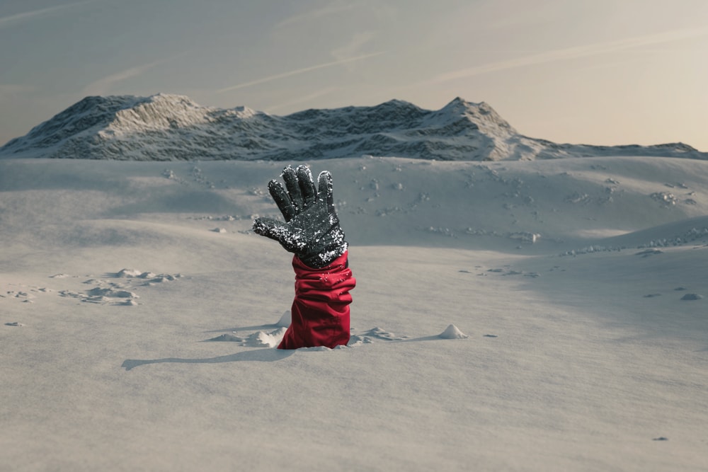 a buried hiker stretching out his hand in the snow 