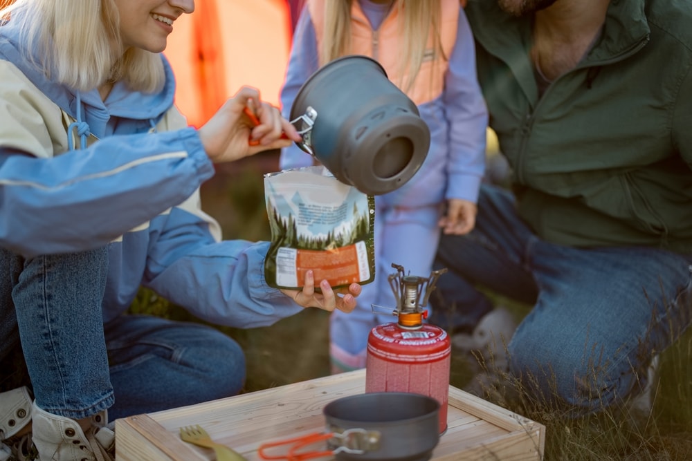 a camper pouring hot water on a freeze-dried camping food