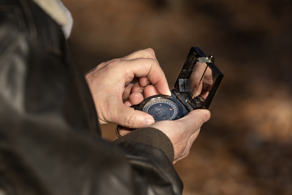 a hiker reading a compass in the forest