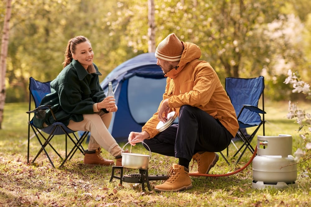 a couple camping and cooking food using propane outdoors