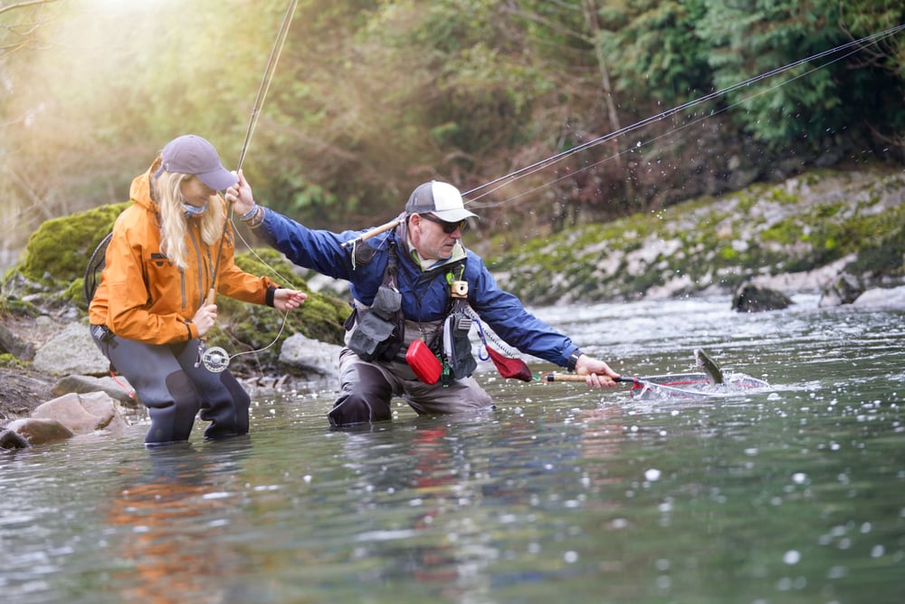 Man guiding a woman tourist doing fly fishing