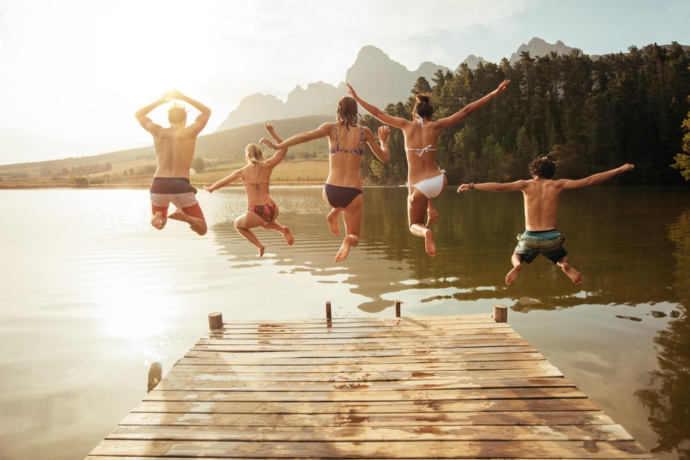 group of friends jumping into the lake