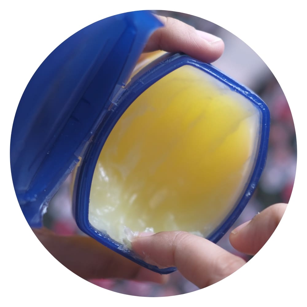 a finger dipping on a jar of Vaseline