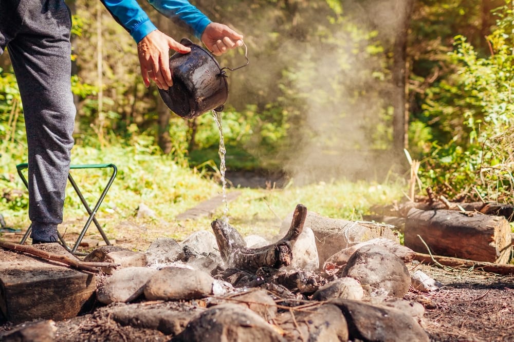 a man putting out a campfire