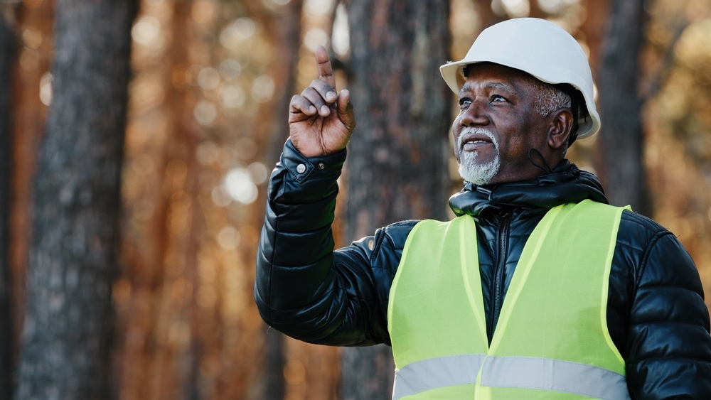 A man pointing at trees in a forest