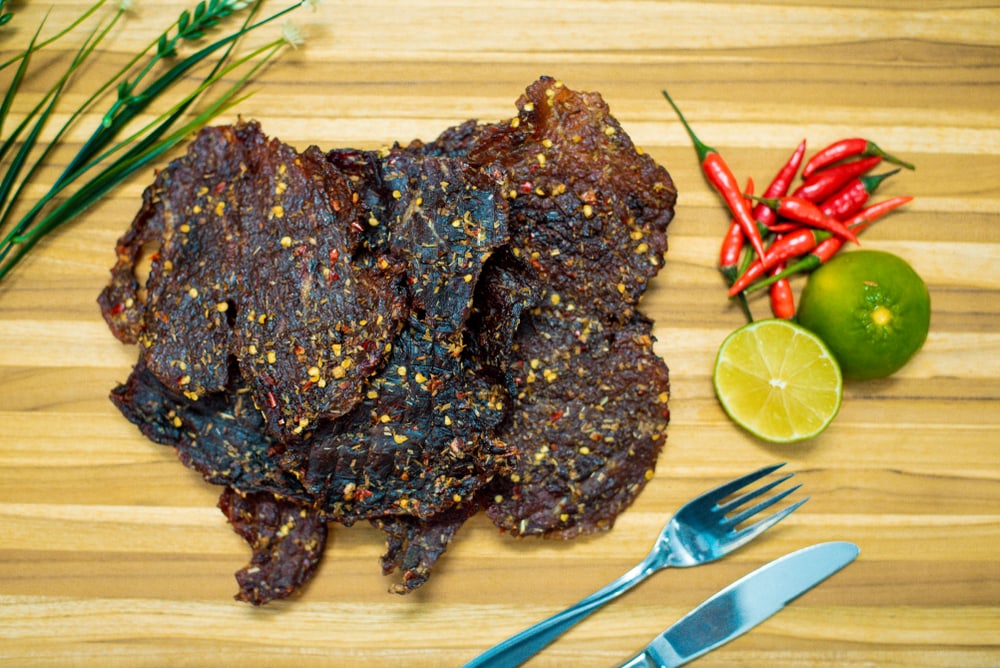 A seasoned beef jerky on s wooden board