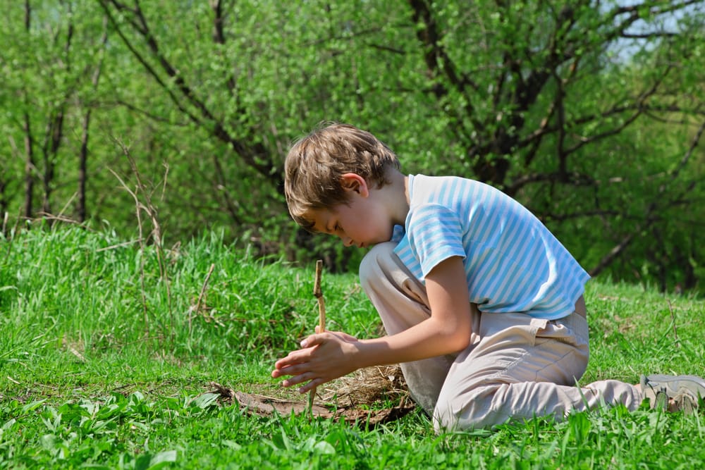 Boy making a fire using a wood stick